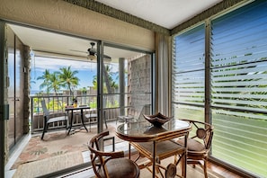 Enjoy a tranquil outdoor space with a round table and four chairs, perfect for dining or relaxing with a view of palm trees and the clear sky.