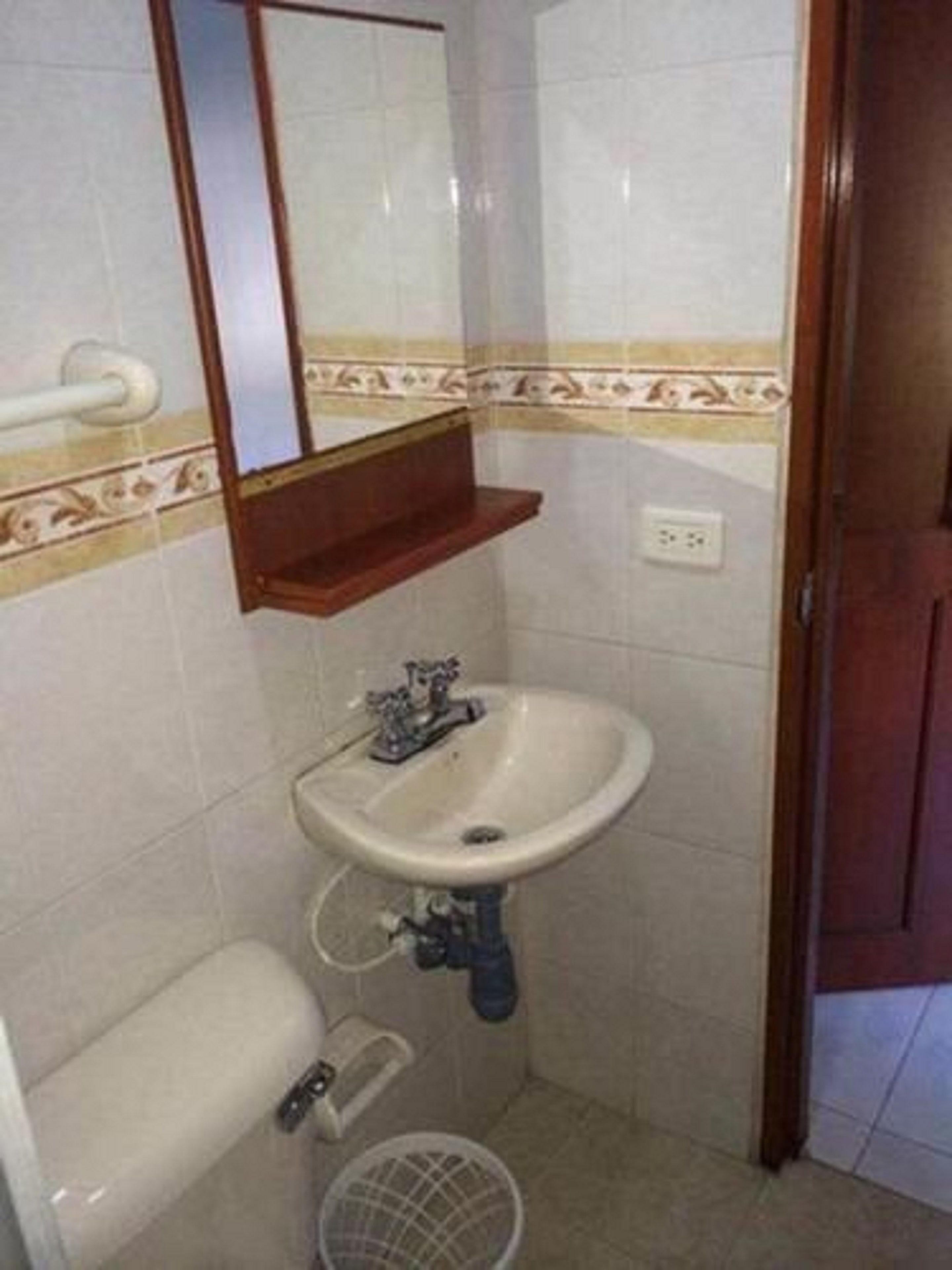 A small bathroom with a sink, mirror, and toilet.