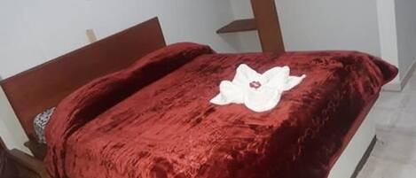 Una cama con una cubierta de terciopelo rojo y una decoración de flores blancas.