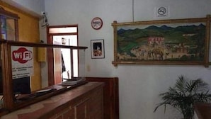 A reception area with a Wi-Fi sign, a framed painting, and a potted plant.