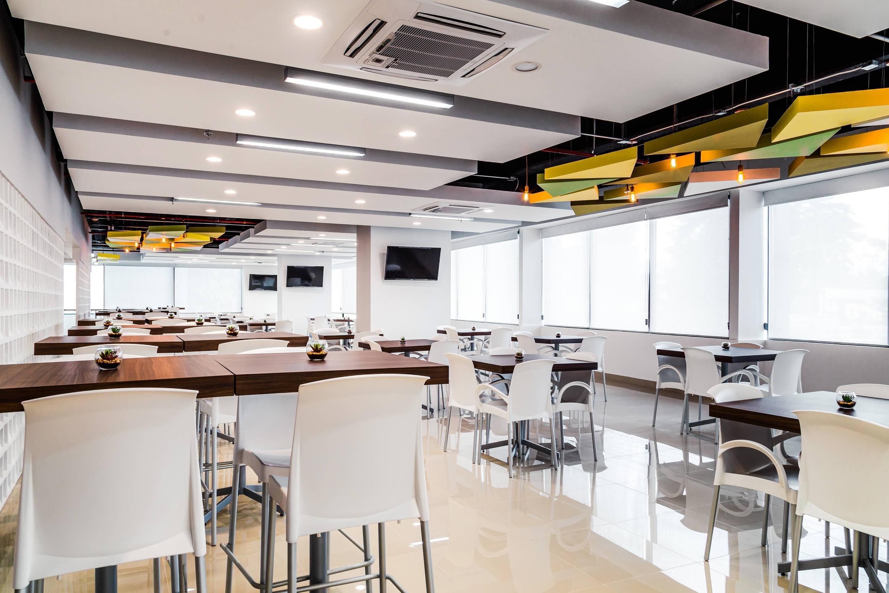 A modern conference room with white chairs, wooden tables, and large windows.