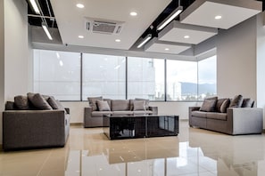 A modern living room with two sofas, a coffee table, large windows, and a city view.