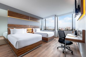 A hotel room with a large bed, a desk, and a view of the city.