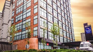 A tall hotel building with a modern design, featuring numerous windows and a brick facade.