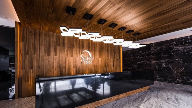 A reception area with a wooden wall, a marble floor, and a modern chandelier.