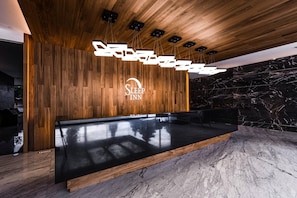 A reception area with a wooden wall, a marble floor, and a modern chandelier. - Sleep Inn Ciudad de México (Mexico City)