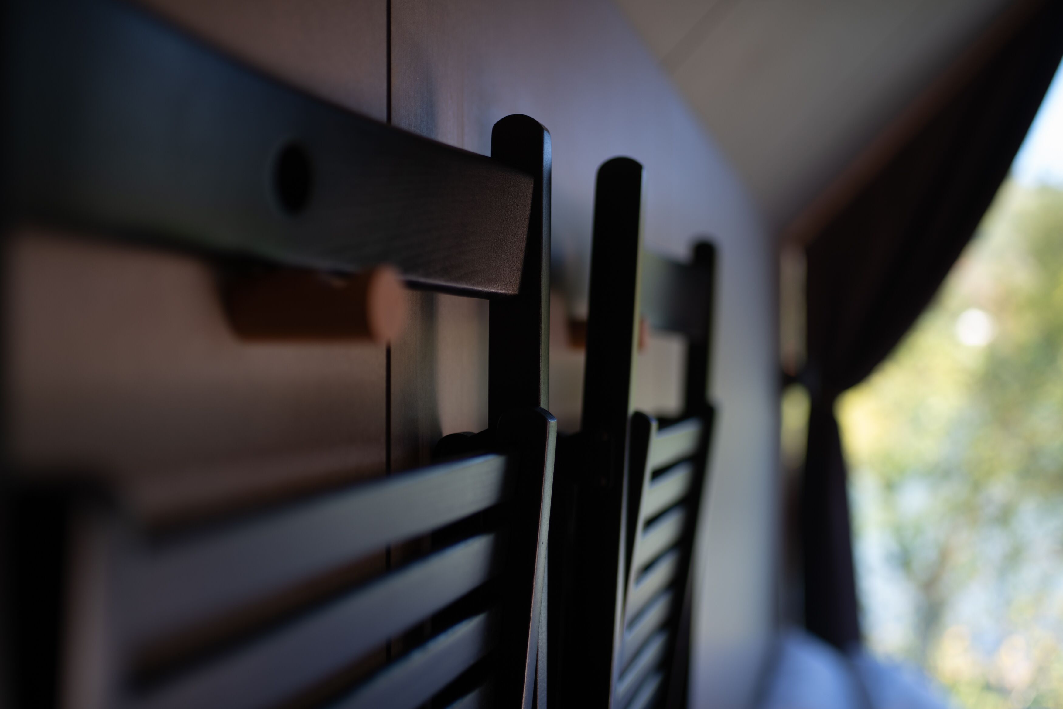A close-up of a wooden chair with a slatted backrest and a metal support structure.