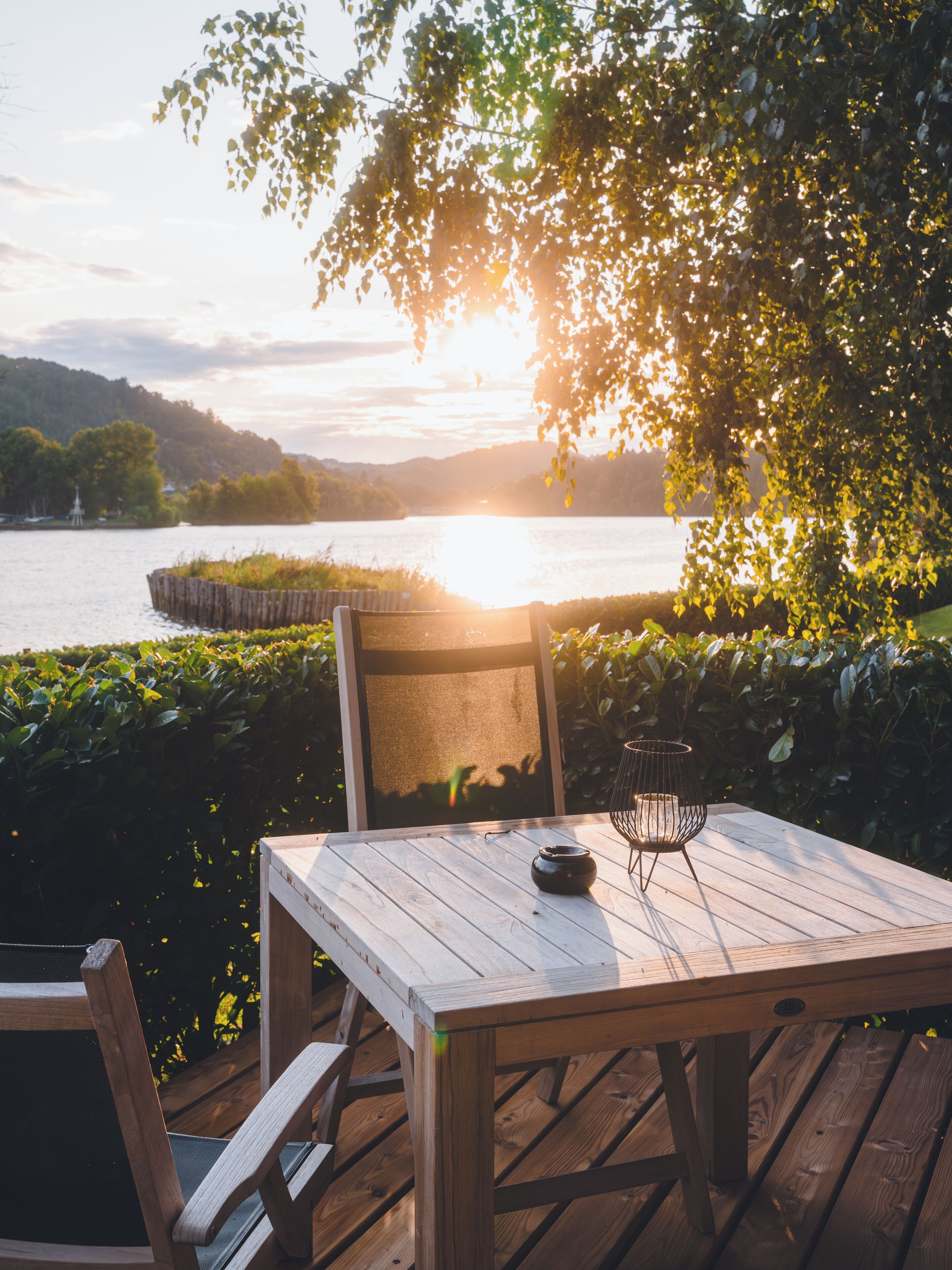 A wooden deck with a table and chairs overlooking a body of water.