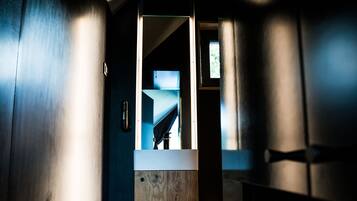A narrow hallway with a wooden door leading to a bathroom.