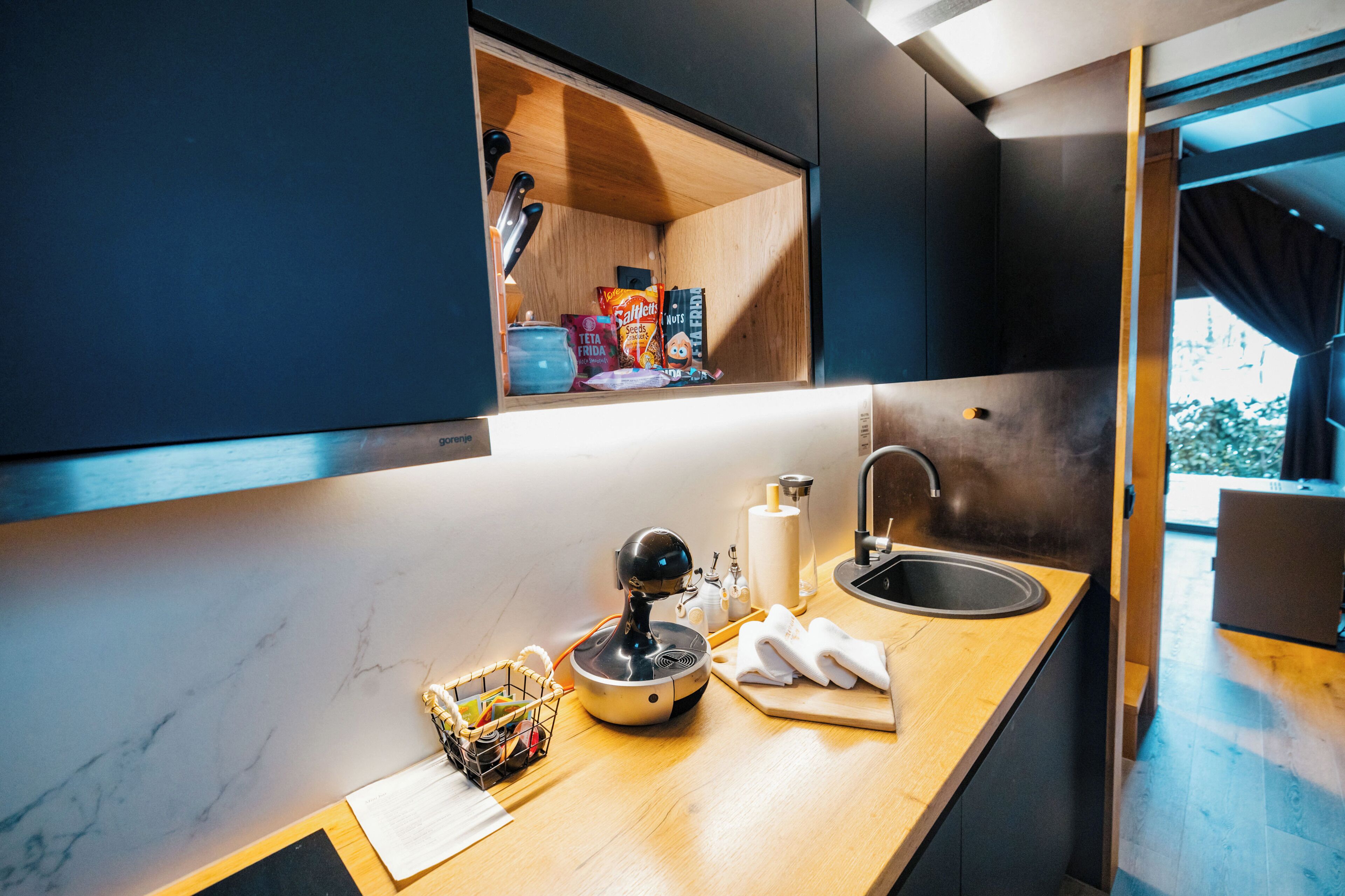 A modern kitchen with a built-in oven, a sink, and a window above the counter.