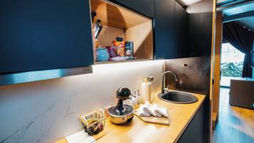 A modern kitchen with a built-in oven, a sink, and a window above the counter.