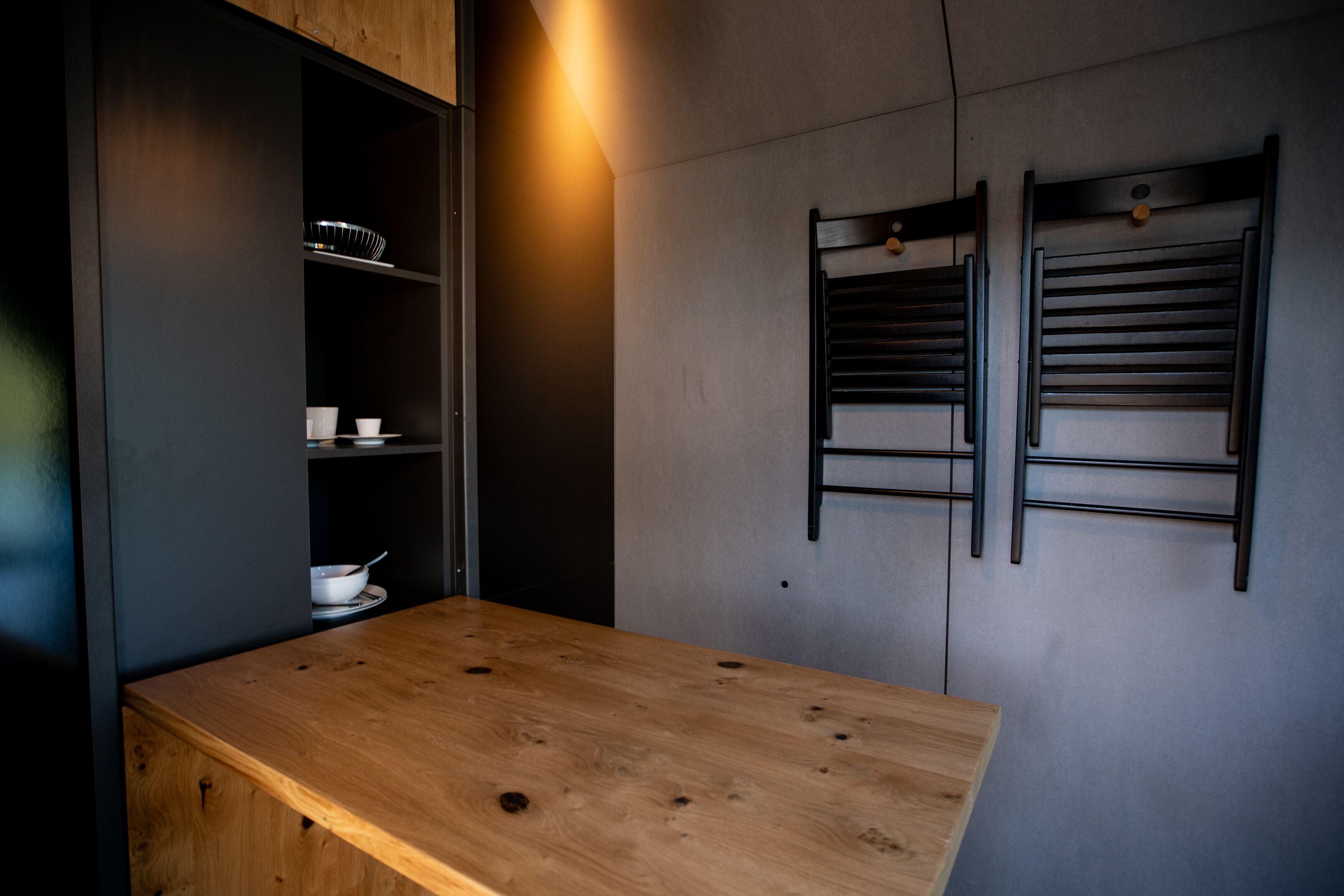 A modern kitchen with a wooden countertop, built-in shelves, and a wall-mounted rack.