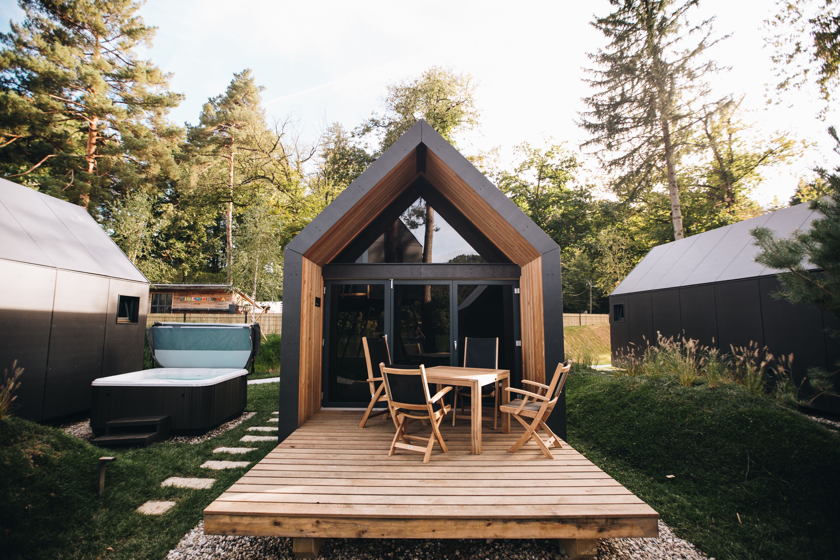 Una terraza de madera con una mesa y sillas, rodeada de un bosque.