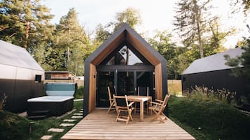 Una terraza de madera con una mesa y sillas, rodeada de un bosque.