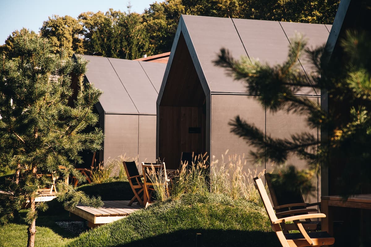 Une cabane moderne dotée d’un toit en pente, entourée d’un jardin bien entretenu et d’un espace extérieur aménagé pour se détendre.