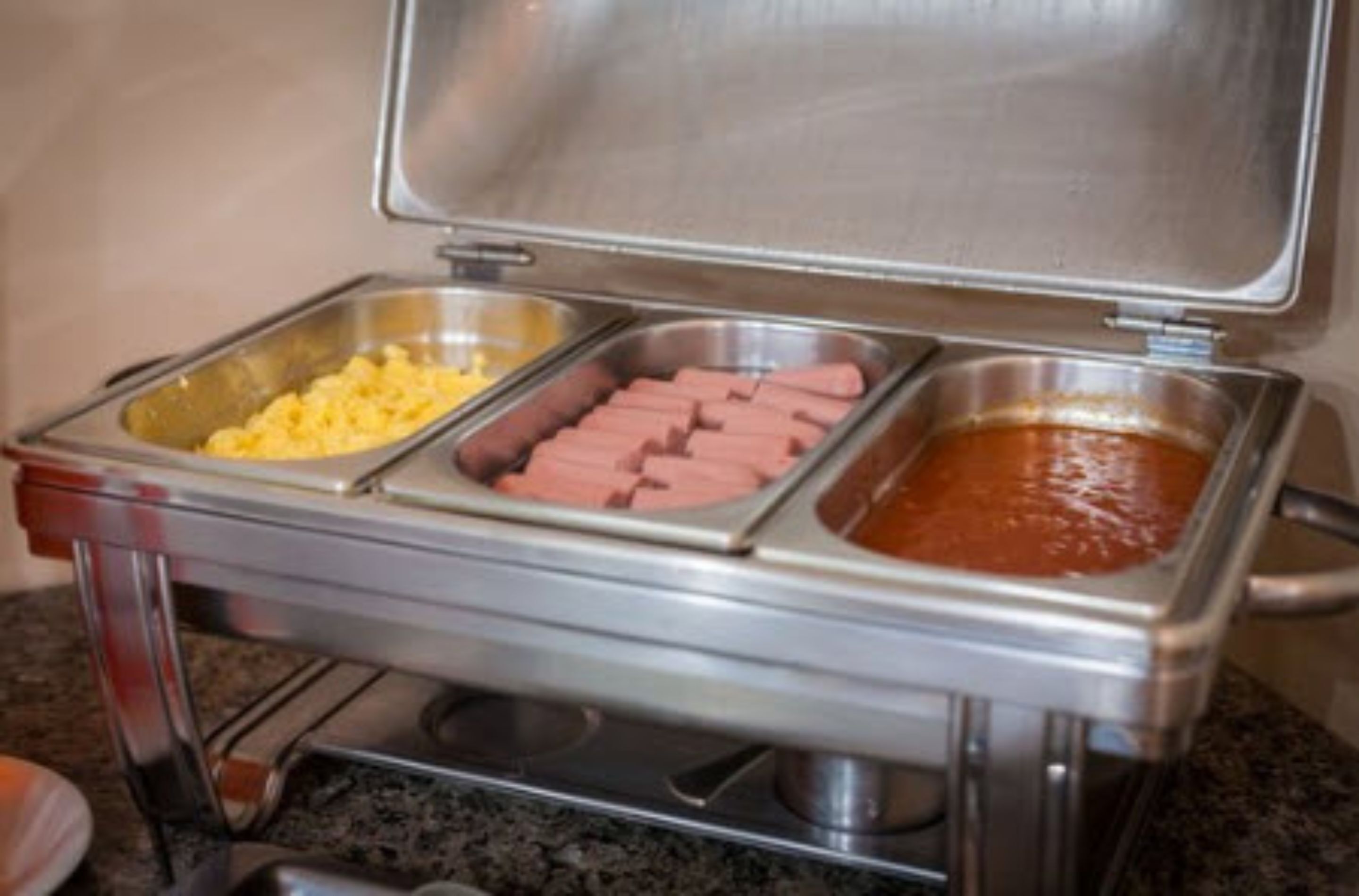 A buffet with three food containers: scrambled eggs, hot dogs, and chili.