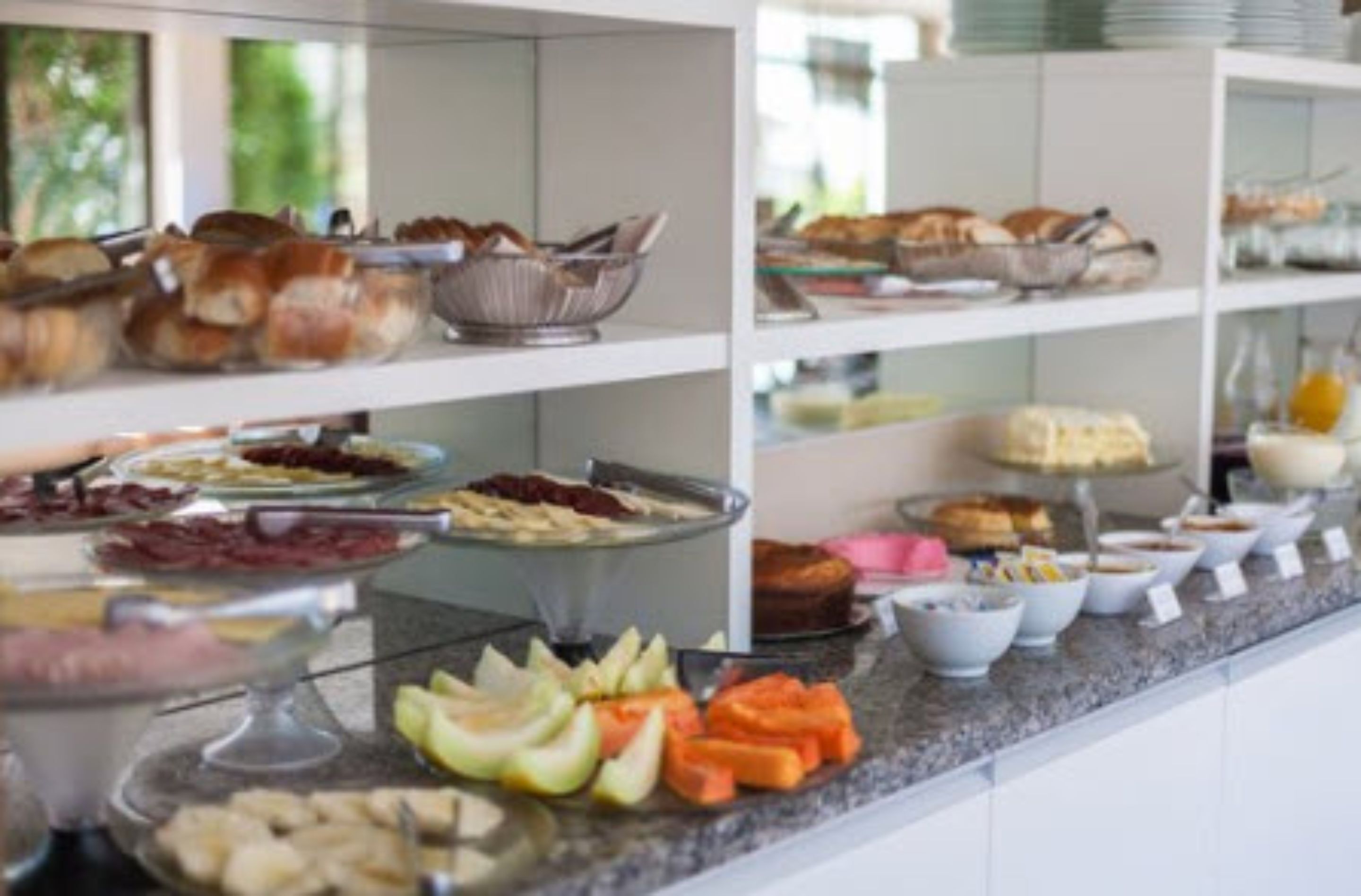 A buffet with various food items including fruits, cheeses, and breads.