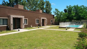 Un edificio moderno con piscina, césped cuidado y cielo despejado.