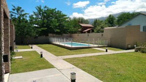 Un jardin avec une piscine, un mur en briques et une maison en arrière-plan.