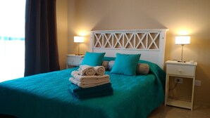 Une chambre d’hôtel avec un lit, deux tables de chevet avec des lampes, une tête de lit et une fenêtre avec des rideaux.