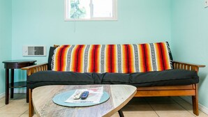 A living room with a sofa, a coffee table, a small table, and a window. - 2330/a (San Diego)