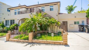 A two-story building with a balcony, a gated entrance with palm trees, and a clear sky. - 2330/a (San Diego)