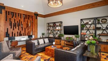 A modern living room with a sectional sofa, a coffee table, and a TV. There are shelves with decorative items and a wooden accent wall.