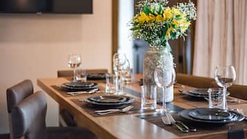 Una mesa de comedor dispuesta con platos, vasos y cubiertos, y un florero con flores amarillas en el centro.