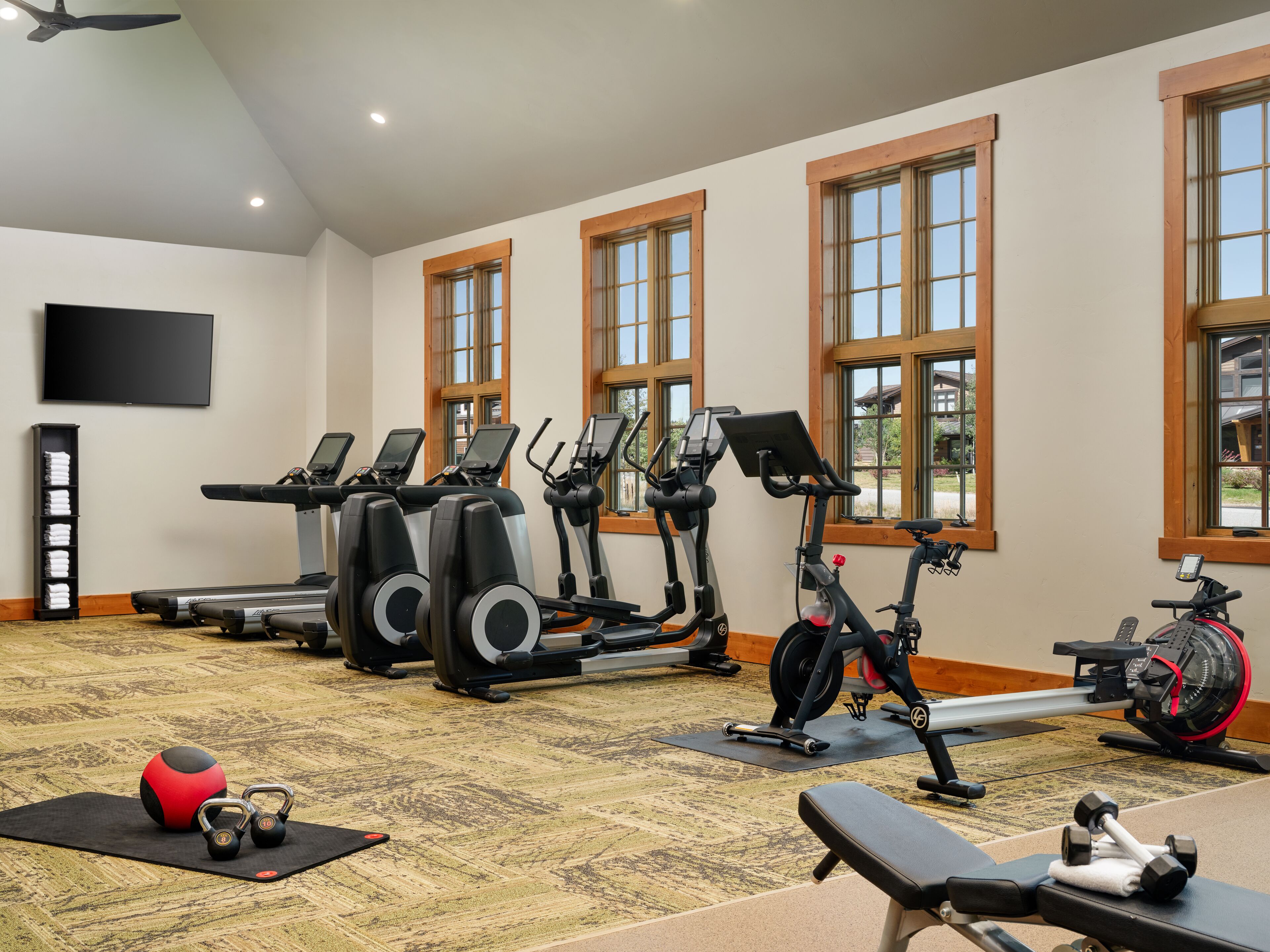 Une salle de sport équipée de tapis de course, de vélos elliptiques, d’un vélo d’appartement et de poids libres.