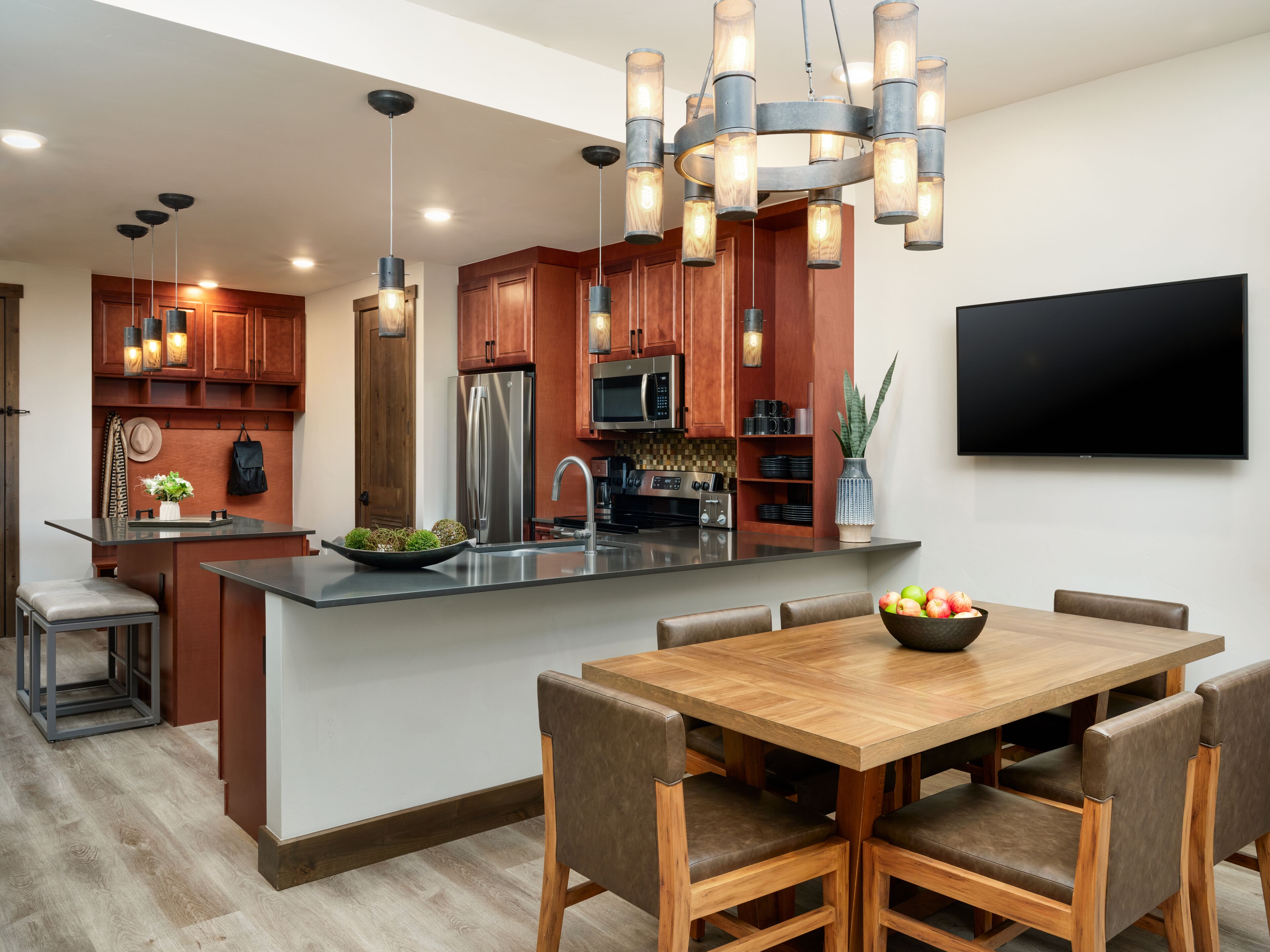 A modern kitchen with a central island, stainless steel appliances, and a dining area with a wooden table and chairs.
