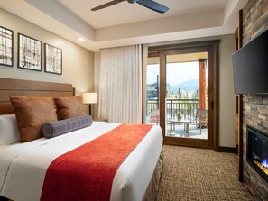 A hotel room with a bed, a TV, a fireplace, and a balcony with a view of the mountains. - Hyatt Vacation Club at The Ranahan (Breckenridge)