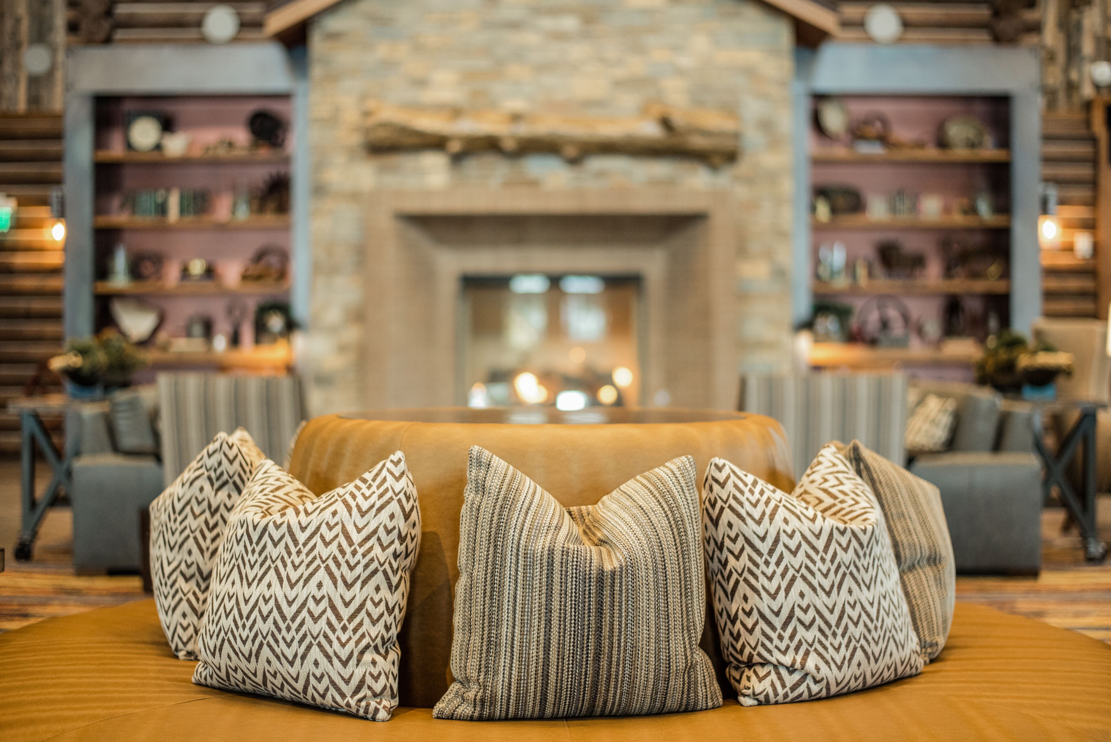 A cozy living room with a fireplace, sofas, and patterned cushions.