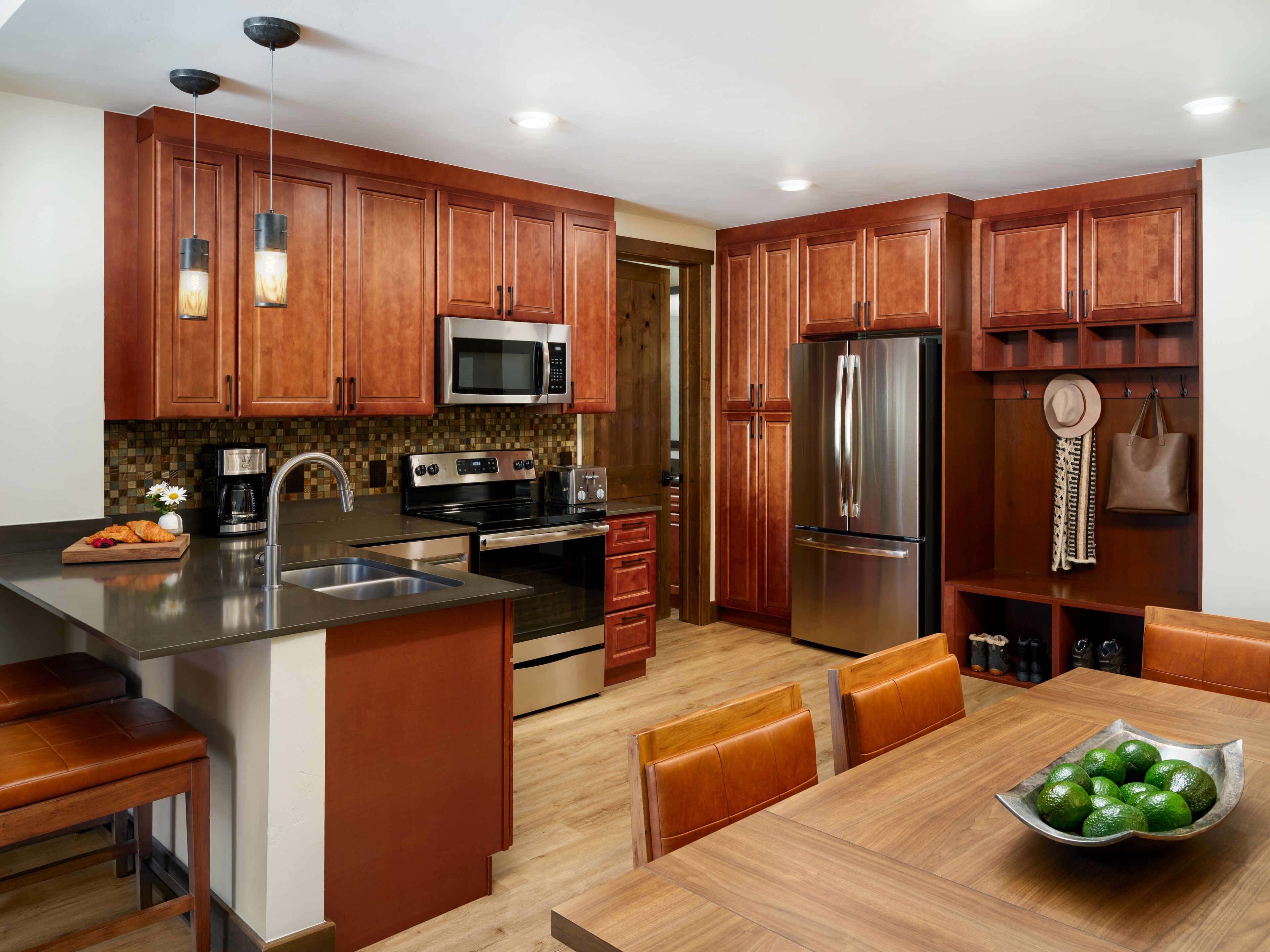 Una cocina moderna con armarios de madera, electrodomésticos de acero inoxidable y un comedor con un tazón de limones.