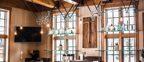 A bar area with wooden beams, hanging light fixtures, and a bar counter with stools.