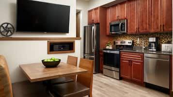 Una cocina moderna con armarios de madera, electrodomésticos de acero inoxidable y un televisor de pantalla plana en la pared.