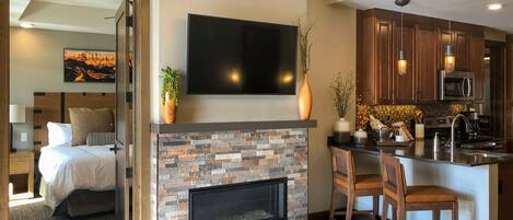 A modern living room with a fireplace, a flat-screen TV, and a dining area with wooden furniture.