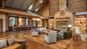 A spacious lobby with a high ceiling, wooden beams, a fireplace, and a variety of seating arrangements. - Hyatt Vacation Club at The Ranahan (Breckenridge)