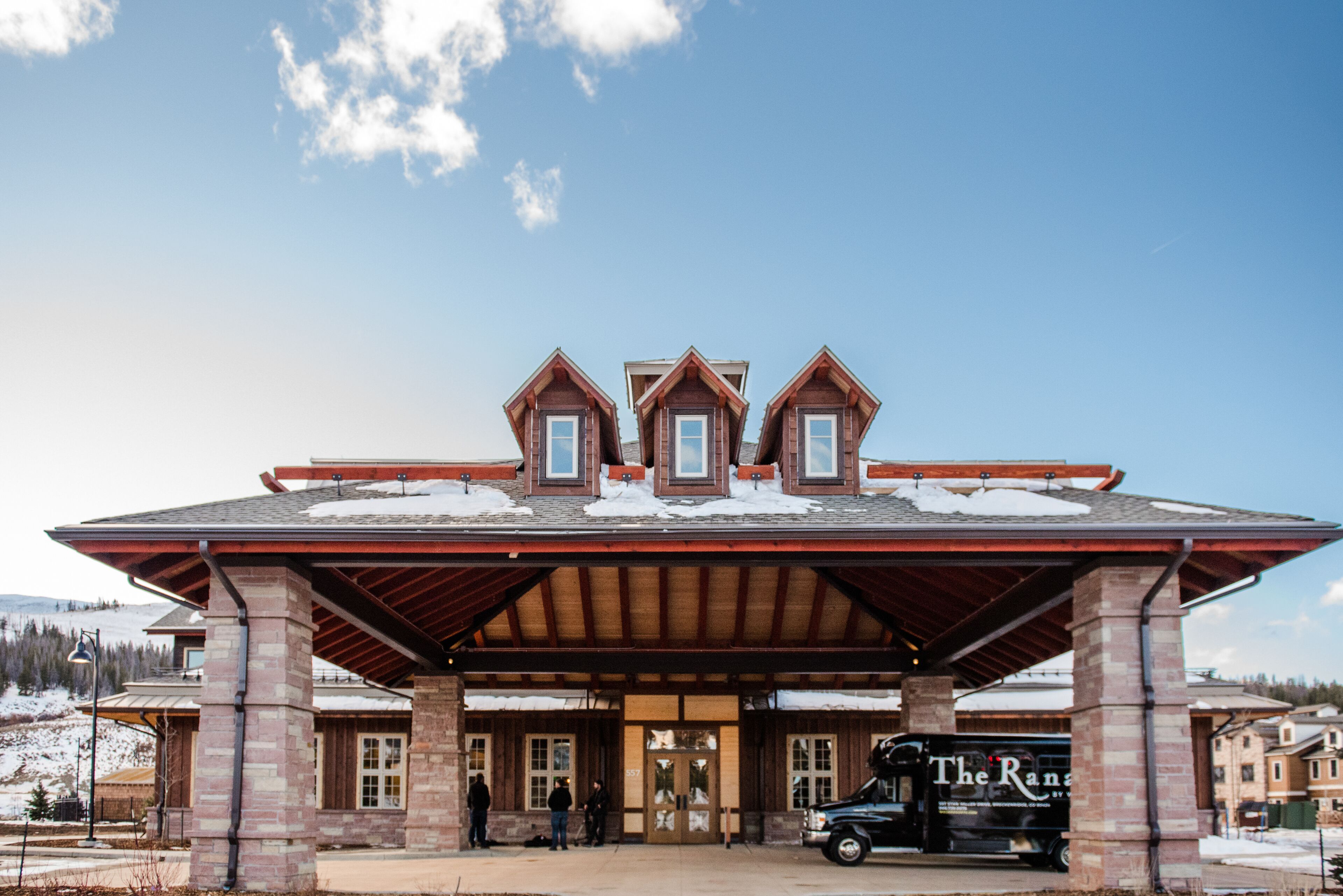 A lodge with a covered entrance, a truck with 'The Ranch' branding, and a snowy landscape.