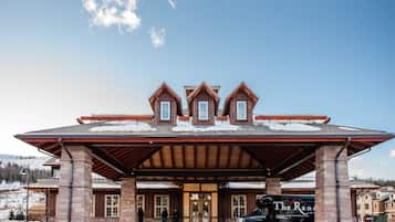 A lodge with a covered entrance, a truck with 'The Ranch' branding, and a snowy landscape.