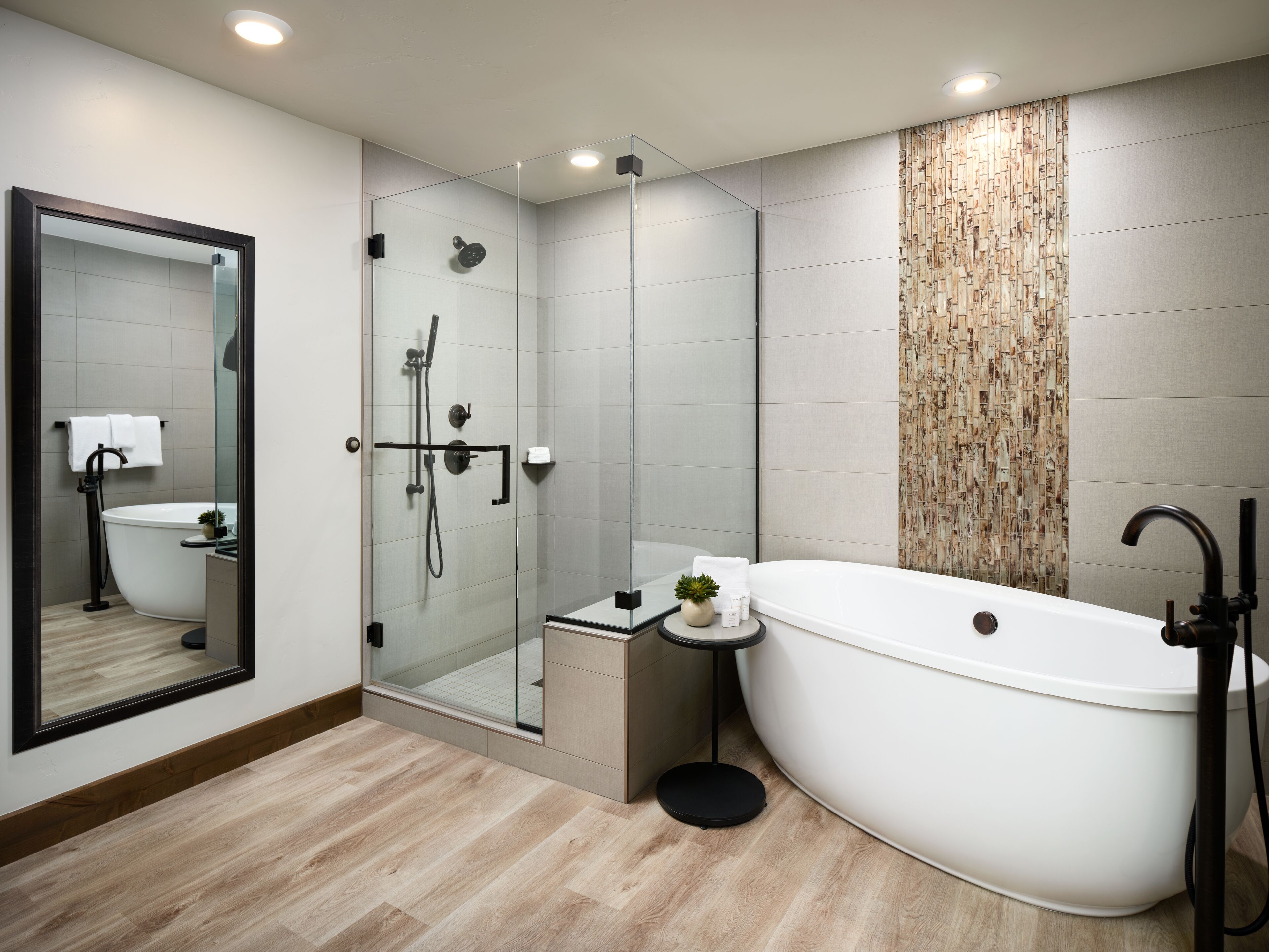 A modern bathroom with a freestanding bathtub, a glass-enclosed shower, and a large mirror.