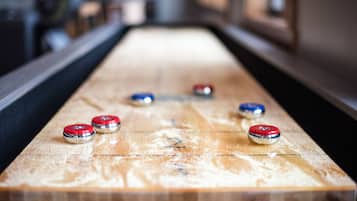 A shuffleboard table with six pucks in red, blue, and silver colors.