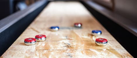 A shuffleboard table with six pucks in red, blue, and silver colors.