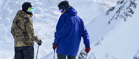 Two skiers on a snowy slope with a mountain in the background.