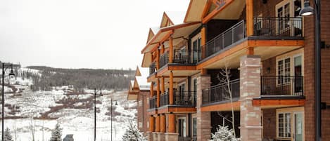 A multi-story building with a wooden facade, balconies, and a view of a snowy landscape.