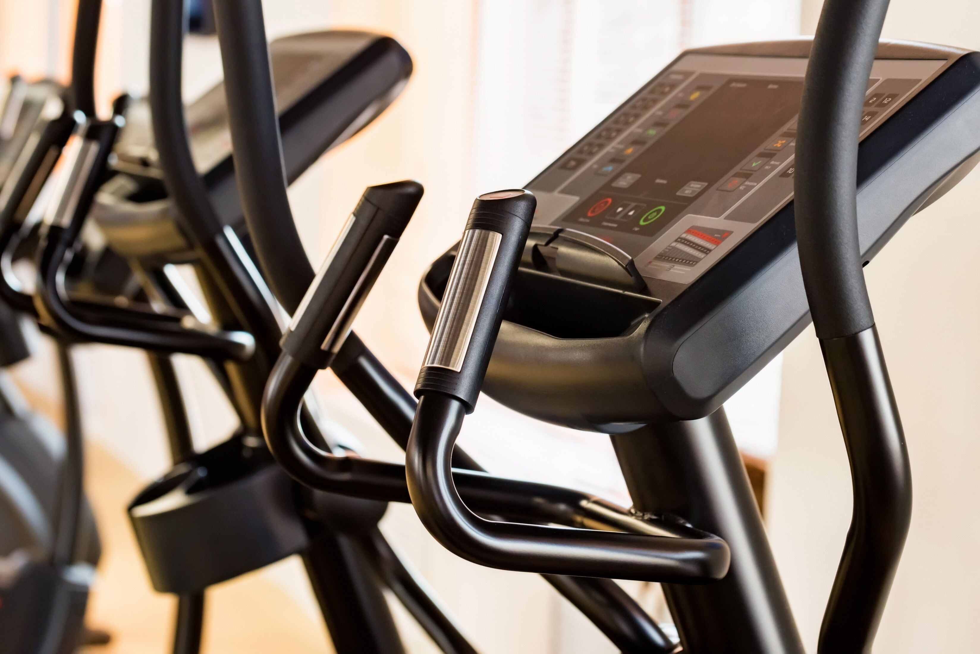Eine Reihe stehender Ergometer mit digitalen Anzeigen und Bedieneinheiten.