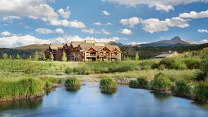 A lodge with multiple wooden cabins, a small stream, and mountains in the background. - Hyatt Vacation Club at The Ranahan (Breckenridge)