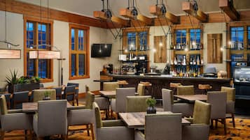 A restaurant with a bar area, wooden beams, and a large window.
