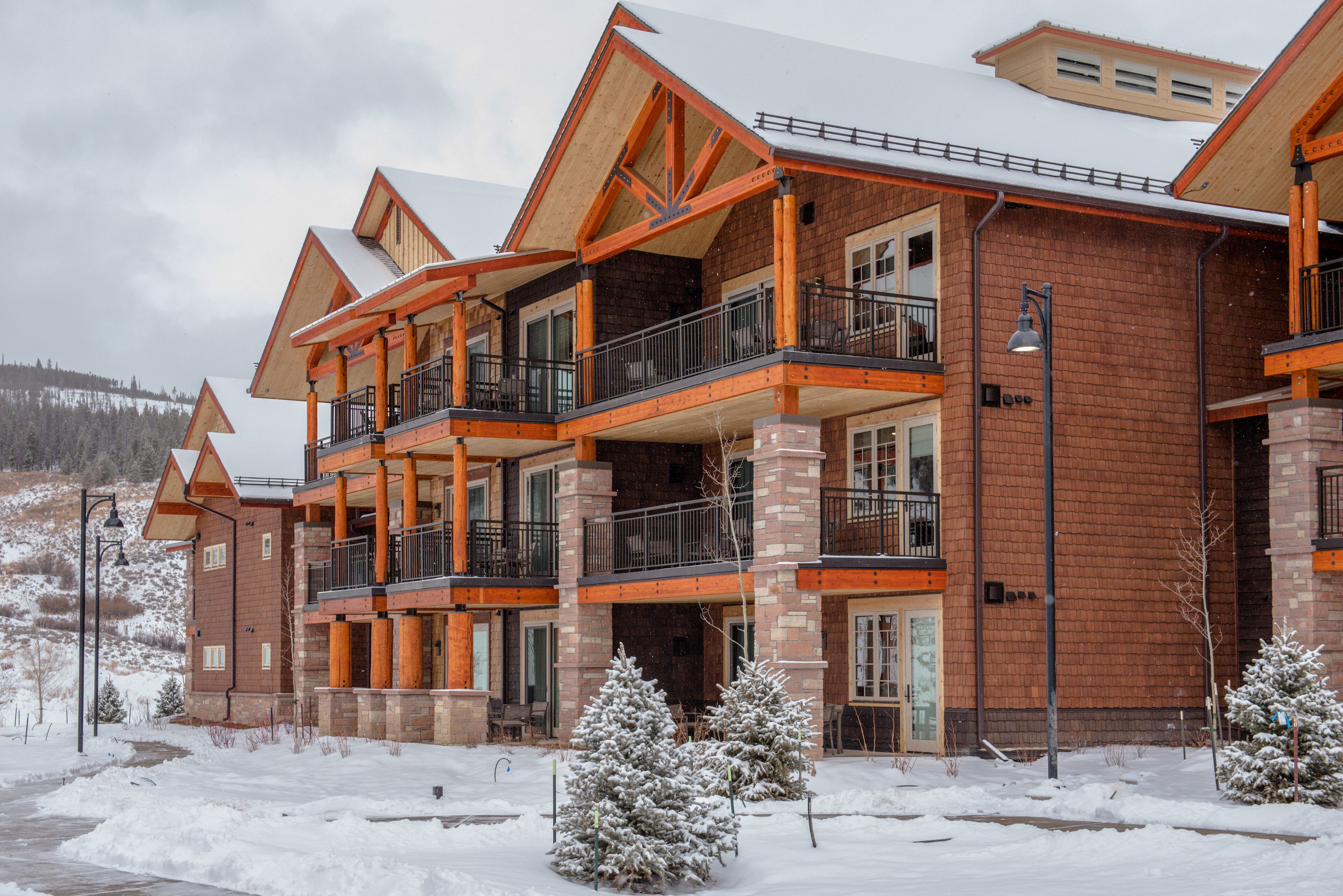 A multi-story building with a brick exterior and wooden accents, featuring balconies and large windows.