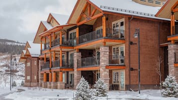 A multi-story building with a brick exterior and wooden accents, featuring balconies and large windows.