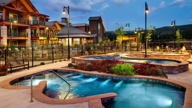 A hotel with multiple balconies, outdoor pools, and a well-lit patio area. - Hyatt Vacation Club at The Ranahan (Breckenridge)
